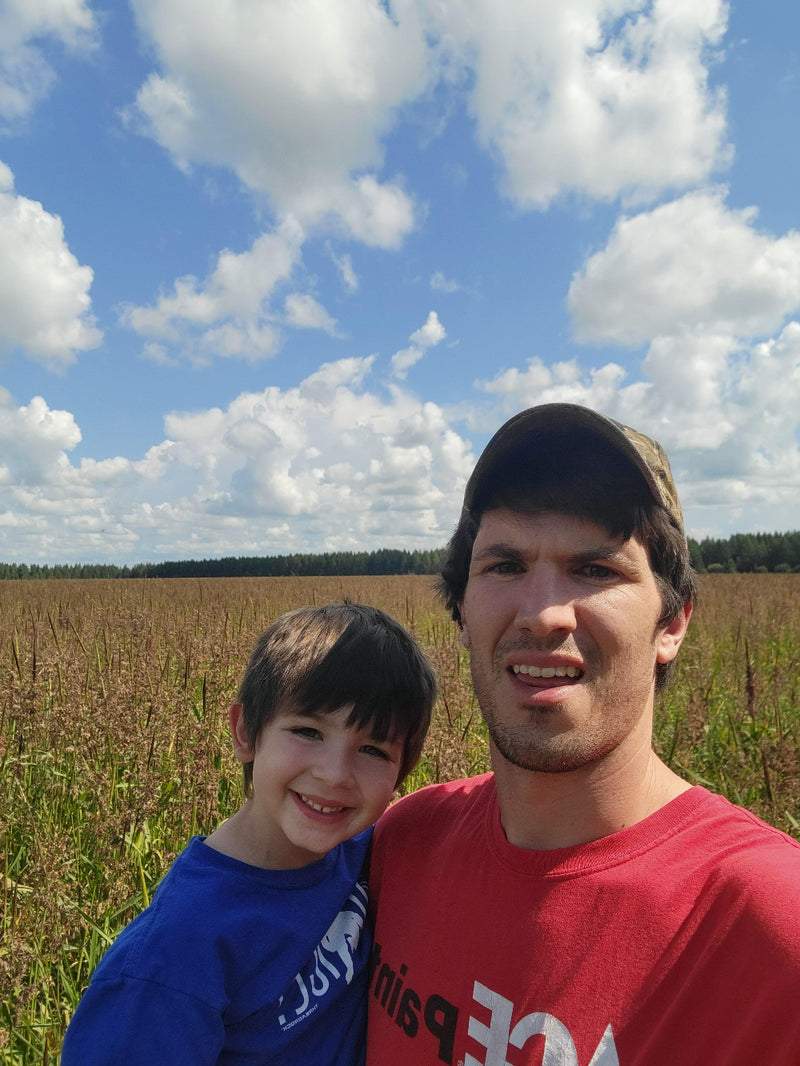 Two people standing outdoors with a clear blue sky and clouds in the background