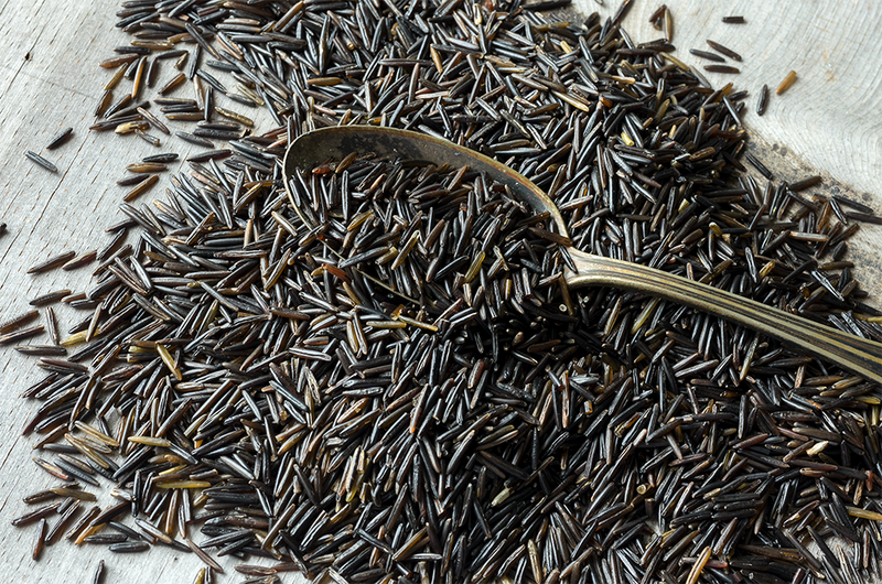 Spoonful of wild rice on a wooden surface